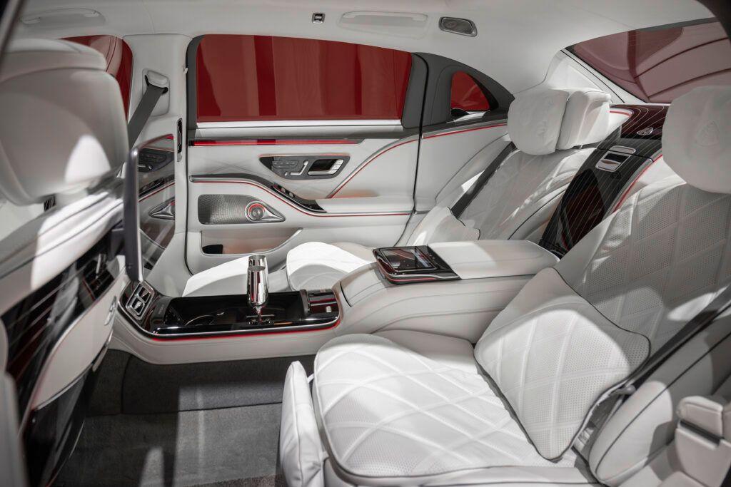 Luxurious car interior with white leather seats, ambient lighting, and advanced controls.