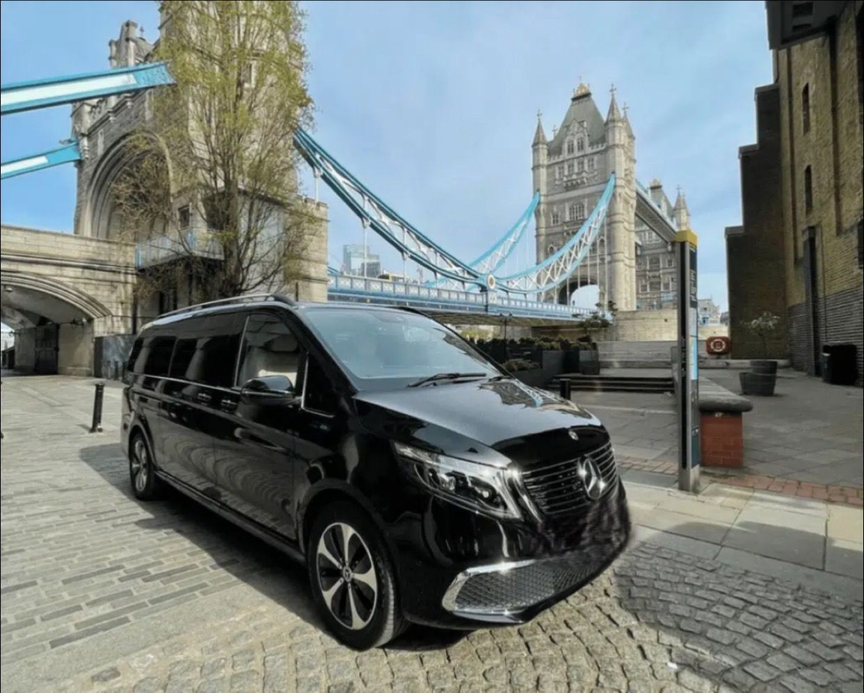 Black Mercedes van parked near Tower Bridge in London on a sunny day.